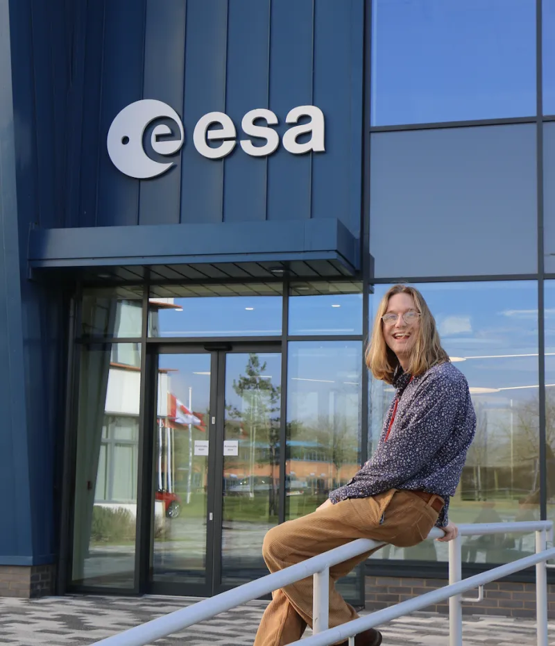 Jools Clarke sitting on a railing outside the ESA building, Harwell Campus UK